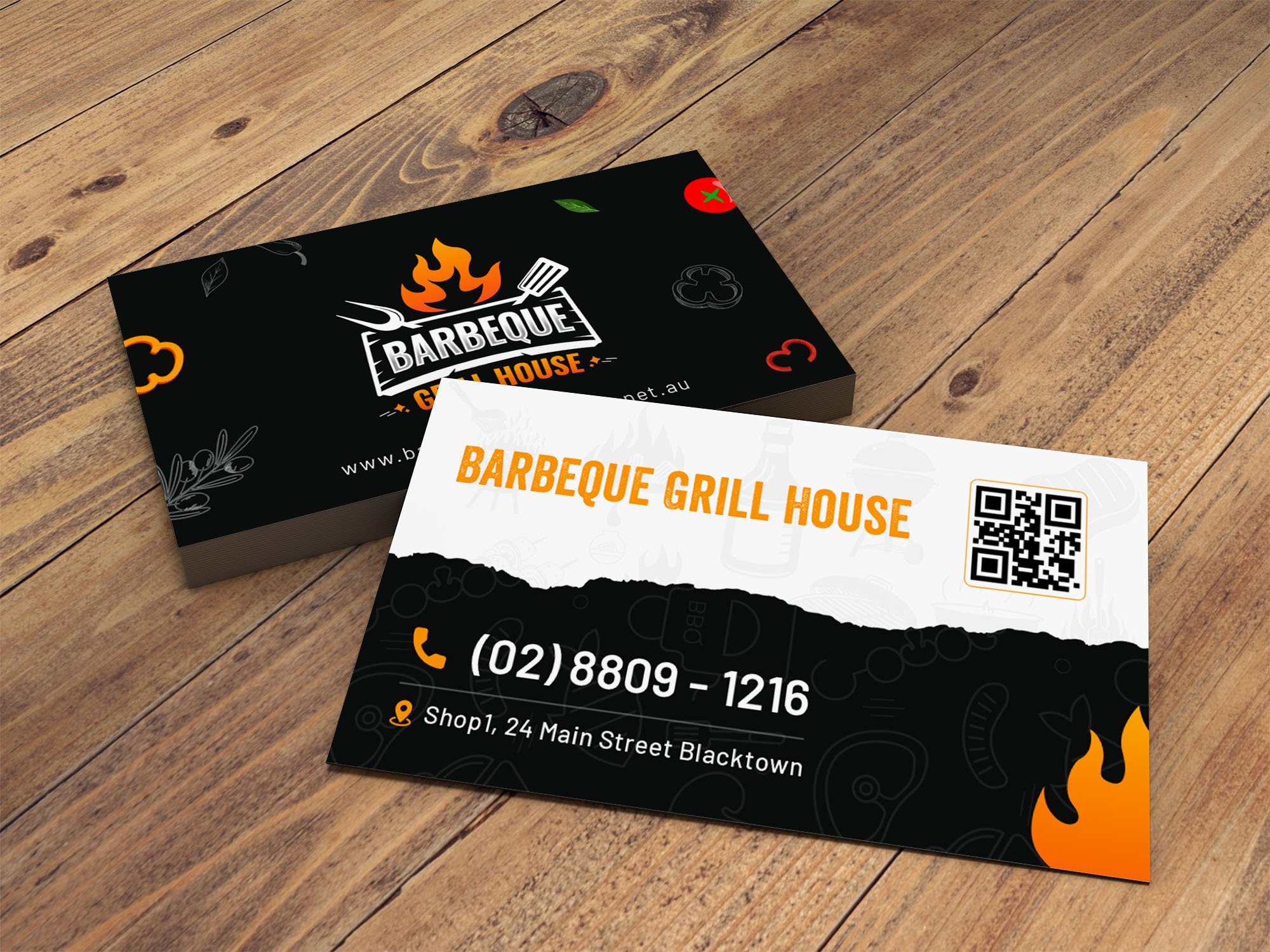 A stack of business cards for Barbeque Grill House on a wooden surface, featuring a flaming grill logo, contact number, address, and a QR code on the front of the card.