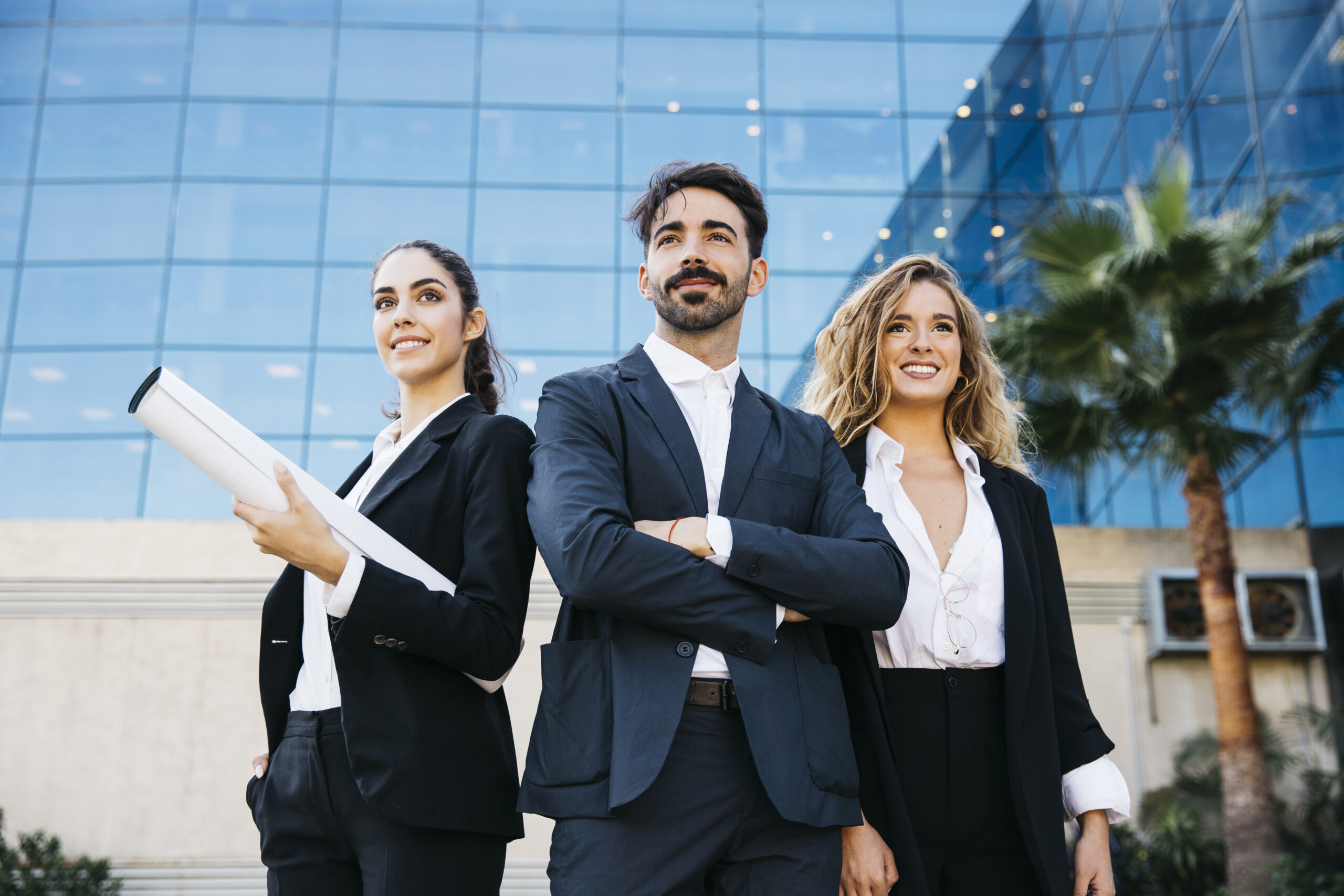 group of 3 professionals wearing professional attires are standing in front of corporate big building with confident and smile